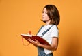 Pretty young beautiful woman standing, writing, take notes, holding textbook notebook organizer in hand and pen Royalty Free Stock Photo