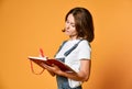 Pretty young beautiful woman standing, writing, take notes, holding textbook notebook organizer in hand and pen Royalty Free Stock Photo