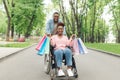 Pretty young black woman in wheelchair holding gift bags after shopping with her boyfriend, copy space Royalty Free Stock Photo