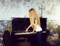 pretty young blond real girl at piano in old-style rusted interior, vintage concept