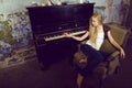 Pretty young blond real girl at piano in old-style rusted interior, vintage concept