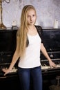 pretty young blond real girl at piano in old-style rusted interior, vintage concept