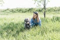 Pretty young blond woman resting with fluffy gray dog on green lawn in summer Royalty Free Stock Photo