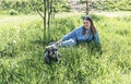 Pretty young blond woman resting with fluffy gray dog on green lawn in summer Royalty Free Stock Photo