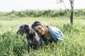 Pretty young blond woman resting with fluffy gray dog on green lawn in summer Royalty Free Stock Photo