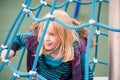 Pretty young blonde girl playing on a rope climbing frame Royalty Free Stock Photo