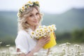 Pretty young blonde woman with camomiles in white blooming field. girl in camomile wreath Royalty Free Stock Photo