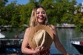 Pretty young blonde woman with straw hat and white dress with red print is having fun doing different poses with the hat close to Royalty Free Stock Photo