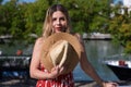 Pretty young blonde woman with straw hat and white dress with red print is having fun doing different poses with the hat close to Royalty Free Stock Photo