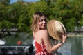 Pretty young blonde woman with straw hat and white dress with red print is having fun doing different poses with the hat close to Royalty Free Stock Photo