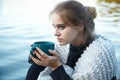 Young blonde woman wearing scarf holding coffee cup, warming up and drinking coffee or tea Royalty Free Stock Photo