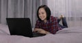 Young woman lying on bed and having video chat using webcam on laptop computer Royalty Free Stock Photo