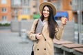 Pretty young woman holding laptop and a cup of coffee and files walking on the street Royalty Free Stock Photo