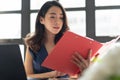 Pretty young business woman holding and looking at red clipboard or document folder. Attractive Beautiful Asian female working in Royalty Free Stock Photo