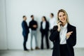 Pretty young business woman standing in the office and using mobile phone in front of team Royalty Free Stock Photo