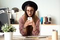 Pretty young business woman using her mobile phone while drinking coffee in the office. Royalty Free Stock Photo