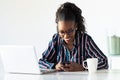 Pretty young business woman using her smartphone while working with laptop in the office Royalty Free Stock Photo