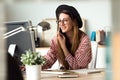 Pretty young business woman working with laptop while using her mobile phone in the office. Royalty Free Stock Photo