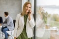 Young business woman standing in the office and using mobile phone in front of her team Royalty Free Stock Photo