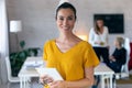 Pretty young businesswoman looking at camera. In the background, her colleagues working in the office Royalty Free Stock Photo