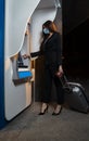 Pretty young businesswoman traveler with face mask at atm