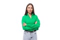 pretty young caucasian brunette lady with makeup dressed in a green shirt and jeans posing on a white background with Royalty Free Stock Photo