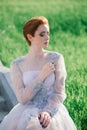 Pretty young caucasian redhead girl in a garden and outside with her wedding bouquet. Beautiful redhead bride Royalty Free Stock Photo
