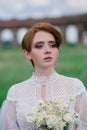 Pretty young caucasian redhead girl in a garden and outside with her wedding bouquet. Beautiful redhead bride Royalty Free Stock Photo