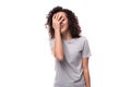 pretty young caucasian woman with black curly hair dressed in a gray t-shirt shy covering her face Royalty Free Stock Photo