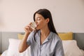 Pretty young caucasian woman drinking water with slice of cucumber sit on bed good morning. Royalty Free Stock Photo