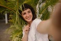 Pretty young caucasian woman looking away taking selfie outdoors in summer. Royalty Free Stock Photo