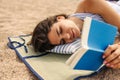 Pretty young caucasian woman reading book relaxing on beach in sunny weather. Royalty Free Stock Photo