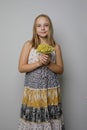 Pretty young child girl wearing summer dress holding yellow flower standing against gray studio wall background, fashion portrait Royalty Free Stock Photo