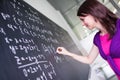 Pretty, young college student writing on the chalkboard/blackboard during a math class Royalty Free Stock Photo