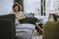 Young curly hair african woman relaxing at home and using mobile phone Royalty Free Stock Photo