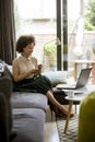 Young curly hair african woman relaxing at home and using mobile phone Royalty Free Stock Photo