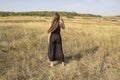 Pretty young dark haired woman in black dress stand in field. Beautiful girl outdoor in the field enjoy with freedom Royalty Free Stock Photo