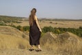 Pretty young dark haired woman in black dress stand in field. Beautiful girl outdoor in the field enjoy with freedom Royalty Free Stock Photo