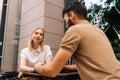 Pretty young dating couple having coffee together and enjoying life sitting at table in street cafe on summer day Royalty Free Stock Photo