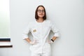 Pretty young doctor with closed eyes leaning against white wall in medical clinic. International doctors day