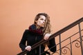 Pretty young fashion woman with long curly hair looking into the distance and posing outdoor near the wall in the street Royalty Free Stock Photo