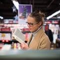 Pretty, young female choosing a good book to buy