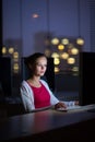Pretty, young female college student using a desktop computer/pc in a college library - burning the midnight oil, working hard to Royalty Free Stock Photo