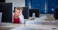 Pretty, young female college student using a desktop computer/pc in a college library (shallow DOF; color toned image) Royalty Free Stock Photo