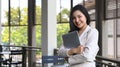 Pretty young female employee holding laptop and smiling to camera while standing on a terrace outside office Royalty Free Stock Photo