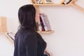 Pretty young female university student  choosing books from the bookshelf in the private modern library Royalty Free Stock Photo