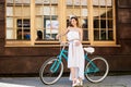 Pretty girl posing near turquoise bike in front of a cafe Royalty Free Stock Photo