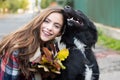 Pretty young girl with big black dog smiling outdoors. Real emotion cheerful portrait cuddling dog pet human. Autumn