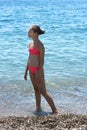 Pretty young girl in bikini standing on the beach near by sea Royalty Free Stock Photo