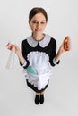 Pretty young girl in cleaning uniform with cleaning tools isolated over white background